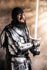 handsome knight in armor holding sword and fighting on black background