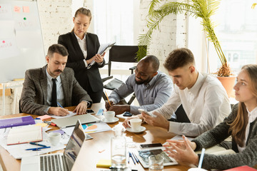 Group of young business professionals having a meeting. Diverse group of coworkers discuss new decisions, future plans and strategy. Creative meeting and workplace, business, finance, teamwork.