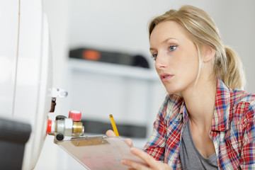 female plumber working on central heating boiler