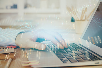 Double exposure of man's hands writing notes with laptop of stock market with forex graph background. Top View. Concept of research and trading.