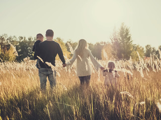 beautiful happy young mother with a baby son, tudler daughter and husband walk in the park at sunset. motherhood. parenthood.