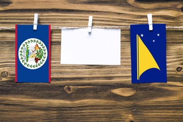 Hanging flags of Belize and Tokelau attached to rope with clothes pins with copy space on white note paper on wooden background.Diplomatic relations between countries.