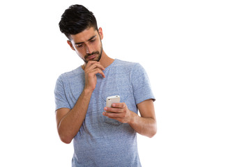 Studio shot of young Persian man using mobile phone