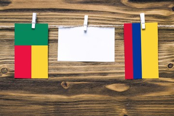 Hanging flags of Benin and Colombia attached to rope with clothes pins with copy space on white...