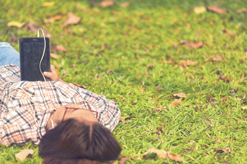 Woman are relaxing in the park by reading books, listening to music, checking facebook mail read...