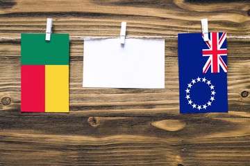Hanging flags of Benin and Cook Islands attached to rope with clothes pins with copy space on white...
