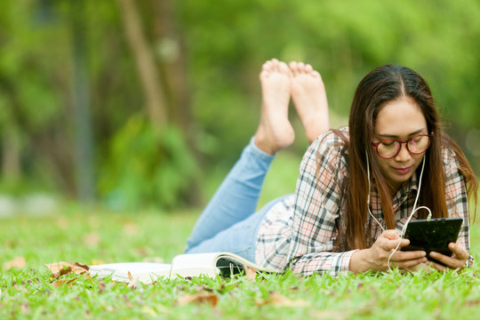  Woman are relaxing in the park by reading books, listening to music, checking facebook mail read news mobile phones.