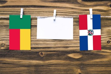 Hanging flags of Benin and Dominican Republic attached to rope with clothes pins with copy space on...