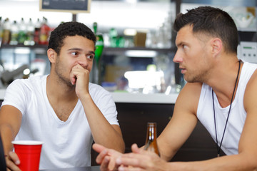 two men sit at a gym bar