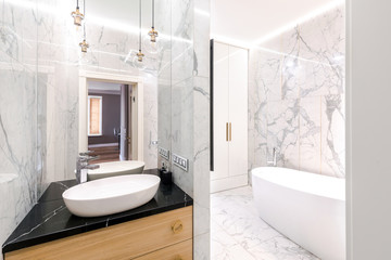 Fototapeta na wymiar Stylish modern luxurious marble bathroom with original fixtures and a washbasin
