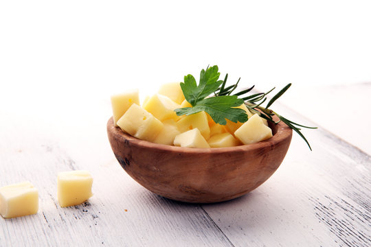 Cheese Cubes In Wooden Bowl With Parsley. Cheese Pieces On Table