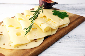 cheese slices on wooden tray with parsley. gauda cheese