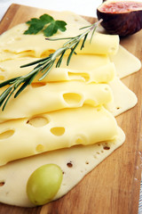 cheese slices on wooden tray with parsley. gauda cheese
