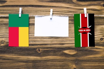 Hanging flags of Benin and Kenya attached to rope with clothes pins with copy space on white note paper on wooden background.Diplomatic relations between countries.