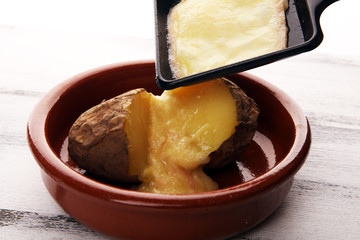 raclette cheese melting on potato served in individual skillets. swiss raclette