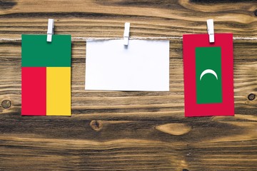 Hanging flags of Benin and Maldives attached to rope with clothes pins with copy space on white...