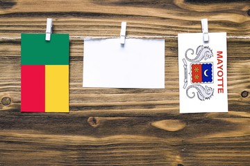 Hanging flags of Benin and Mayotte attached to rope with clothes pins with copy space on white note...