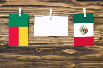Hanging flags of Benin and Mexico attached to rope with clothes pins with copy space on white note...