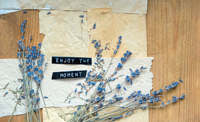 Enjoy the moment. motivation quote. lavender flowers and old paper on rustic wooden background. romantic nostalgic composition. grunge filter. soft selective focus. close up