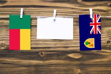 Hanging flags of Benin and Turks And Caicos Islands attached to rope with clothes pins with copy...