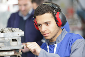 young male manual worker wearing earmuffs at work