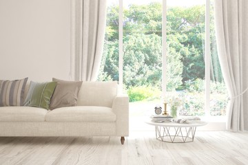 Fototapeta premium Stylish room in white color with sofa and summer landscape in window. Scandinavian interior design. 3D illustration