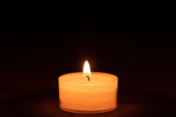 Fototapeta na wymiar Closeup of a candle on a wooden table with dark background - middle