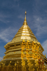 Glistening golden pagoda of a Buddhist temple against a clear blue sky