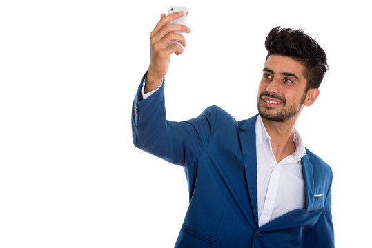 Young handsome bearded Persian businessman in suit taking selfie