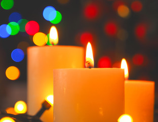 Three burning Advent candles with Christmas lights