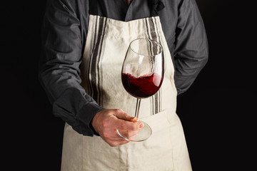 Fototapeta Hombre Camarero sosteniendo una copa de vino tinto en movimiento. Sommelier. Vista de frente	 obraz