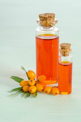 Sea buckthorn and two bottles with sea buckthorn oil on blue table