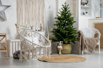 Modern interior design room with Christmas and New Year decorations, toys, gifts, fir tree, hanging swing. Winter holidays composition.