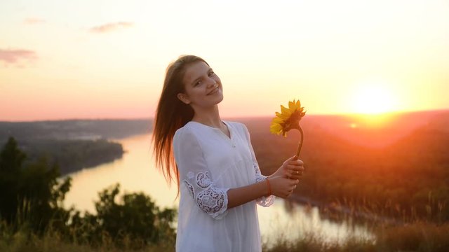 Teen girl with a magic flower at sunset