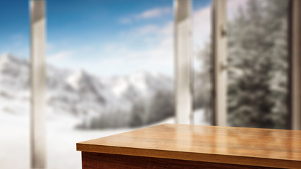Table corner with space for your product. Blurry winter window with the door open. Beautiful landscape of snowy mountains and festive fir with snow covered branches. Place for your products or inscrip