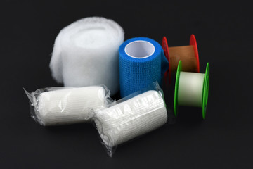 Dressing material for treating injuries like gauze and self-adhesive bandages and adhesive tape on dark back background
