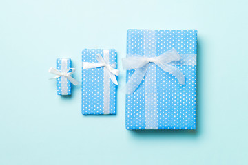 wrapped Christmas or other holiday handmade present in paper with white ribbon on blue background. Present box, decoration of gift on colored table, top view