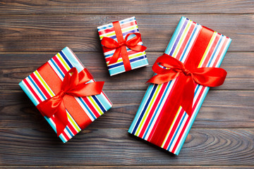 paper gift box with colored ribbon on dark wood background. top view with copy space Christmas...