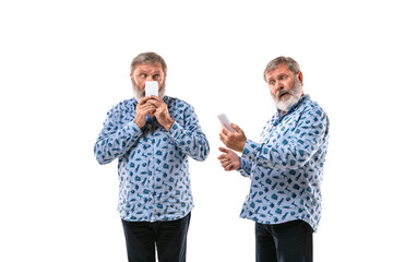 Senior man arguing with himself on white studio background. Concept of human emotions, expression, mental issues, internal conflict, split personality. Half-length portrait. Negative space. Secrets.