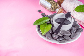 Flat lay composition with spa stones, green leaves and cosmetics, top view copy space