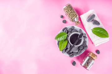 Flat lay composition with spa stones, green leaves and cosmetics, top view copy space