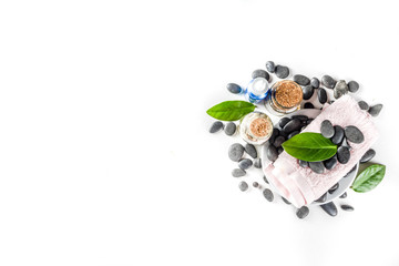 Flat lay composition with spa stones, green leaves and cosmetics, top view copy space