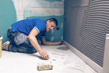Fliesenleger verlegt grosse graue fliesen im einem modernem badezimmer