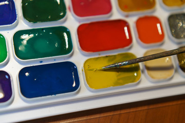 Photography of various colorful and bright paints for drawing and paintbrush. Concepts of education and development of creativity. Red, blue, green, yellow, pink colors.