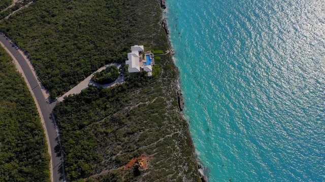 Aerial: Beachfront Mansions Surrounded by Dark Green Plant life and Overlooking the Aquamarine Blue Water - Providenciales, Turks and Caicos