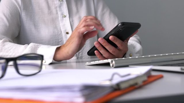 Closeup shot of businesswoman&rsquo;s hands messaging or browsing her cell phone at her office table.