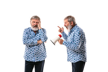 Senior man arguing with himself on white studio background. Concept of human emotions, expression,...