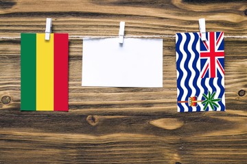 Hanging flags of Bolivia and British Indian Ocean Territory attached to rope with clothes pins with copy space on white note paper on wooden background.Diplomatic relations between countries.