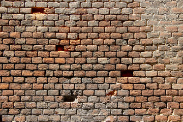 Old damaged brick wall with holes in place of some bricks