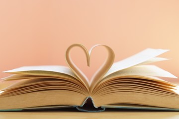 Heart from page of book for valentine's day concept with blurred bright light background 
